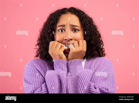Young Black Woman Feeling Scared Biting Nails In Panic On Pink Studio