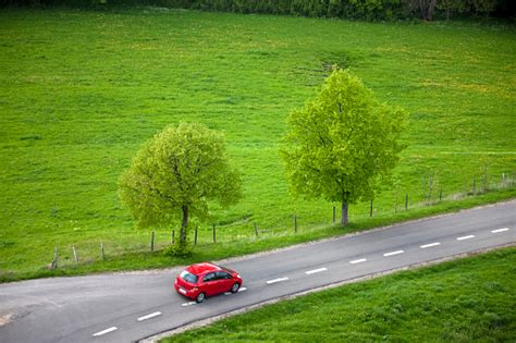 Small Red Car Driving Fast On Country Road Stock Photo