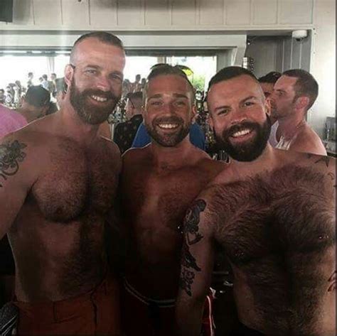 Three Shirtless Men Standing Next To Each Other In Front Of A Group Of