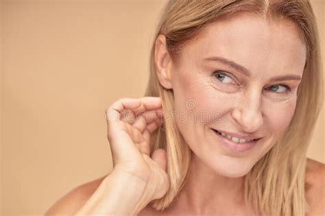 Feeling Attractive Portrait Of A Beautiful Middle Aged Woman Touching Her Hair Looking Aside
