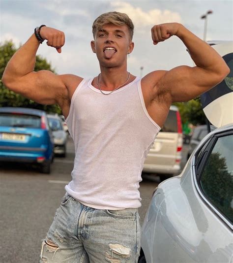 A Man Flexing His Muscles While Standing Next To A Car