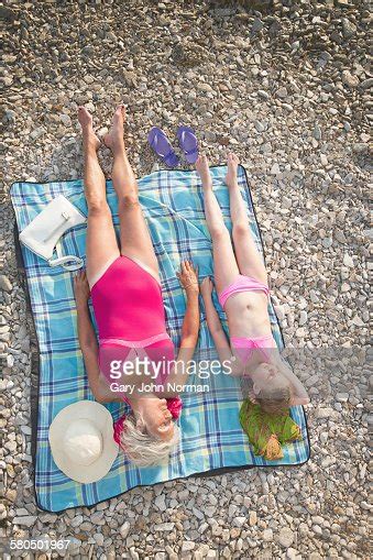 Caucasian Grandmother And Granddaughter Sunbathing On Beach Photo