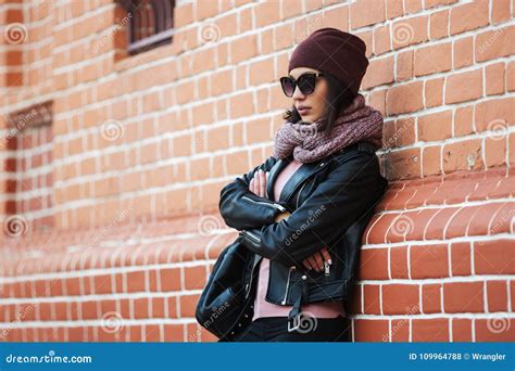 Young Fashion Woman In Black Leather Jacket Leaning On Brick Wall Stock