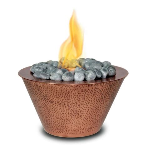 A Copper Bowl With Blue Rocks In It And A Fire Pit On The Side That Is Lit