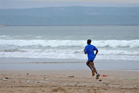 Man Runs Along A Dirty Sandy Beach After A Storm Editorial Photography