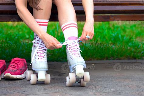Female Skater Binds The Roller Skates On The Bench In A Park 15743191