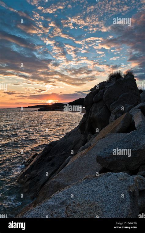 Silhouette Of Sea Rocks With Cloudscape Reflection At Sunset West