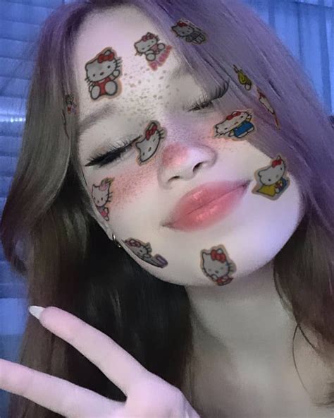 A Woman With Hello Kitty Face Paint On Her Cheek And Hand In Front Of Her Face