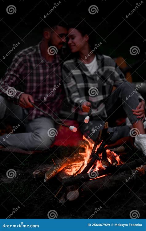 Young Couple In Love Roasting Marshmallows On Campfire On Nature Stock
