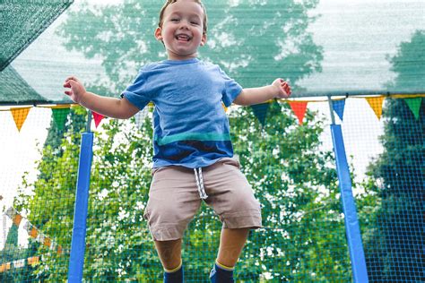 Toddler Boy Jumping On A Trampoline At The Amusement Park By Stocksy