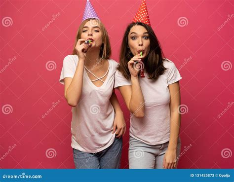 Close Up Portrait Of Blonde And Brunette Young Women With Birthday Hats Having Fun Isolated On