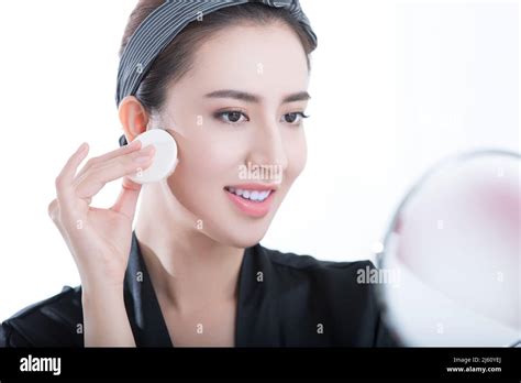 Young Beauty In Front Of A Makeup Mirror Is Applying Powder On White