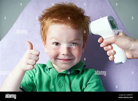 Doctor Measures Temperature Of A Cute Red Haired Freckled Little Boy