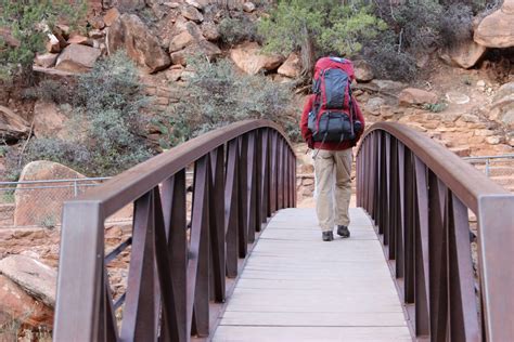 Free Stock Photo of Man with Hiking Backpack Walking Across Bridge