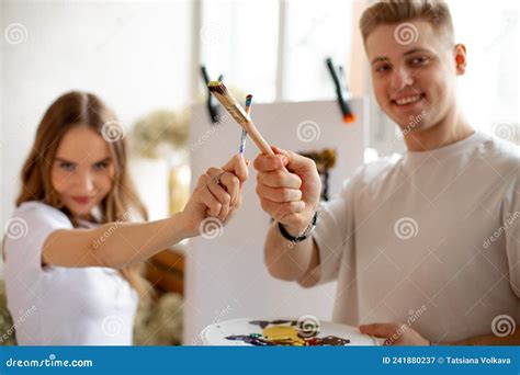 Happy Young Smiling Fair Haired Couple Stand Crossing Brushes While Man