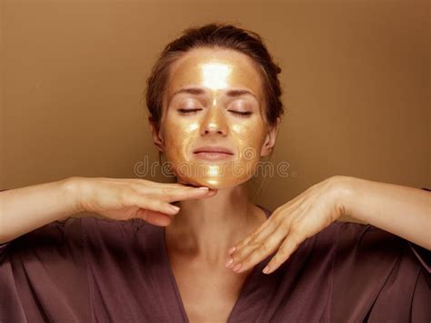Relaxed Elegant Woman With Golden Mask Making Facial Massage Stock