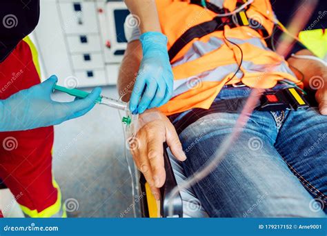 Emergency Doctor Administering Injection Needle In Ambulance Stock