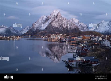 Olstind Mountain Peaks Reflects In Calm Water Of Reine Harbor During