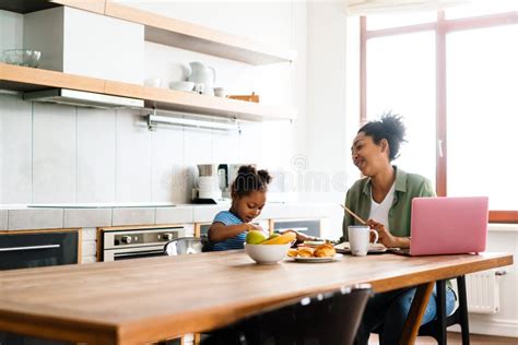 Feliz Madre E Hija Desayunando En La Cocina De La Casa Imagen De