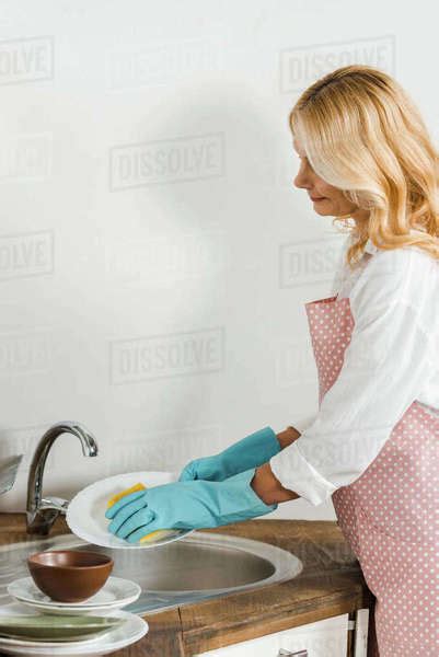 Attractive Mature Woman Washing Dishes In Kitchen Stock Photo Dissolve