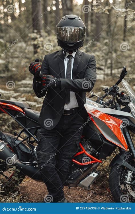 Handsome Biker With Helmet And Dark Motorcycle In Forest Stock Image
