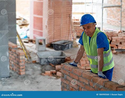 A Construction Worker Stands Leaning Against The Wall Stock Photo