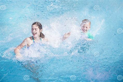 Two Kids Splashing Each Other In The Swimming Pool While On Vacation
