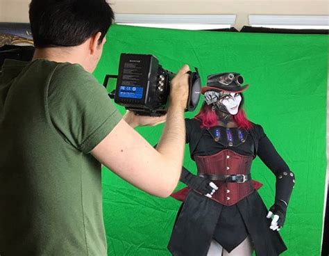 A Man Taking A Photo Of A Woman Dressed As A Pirate In Front Of A Green