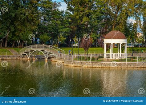A Beautiful Pond With An Artificial Island And An Iron Footbridge In A