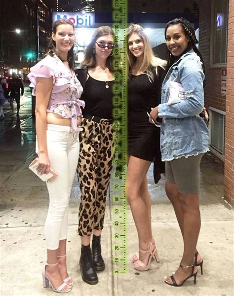 Three Women Standing Next To Each Other In Front Of A Tall Ruler On The