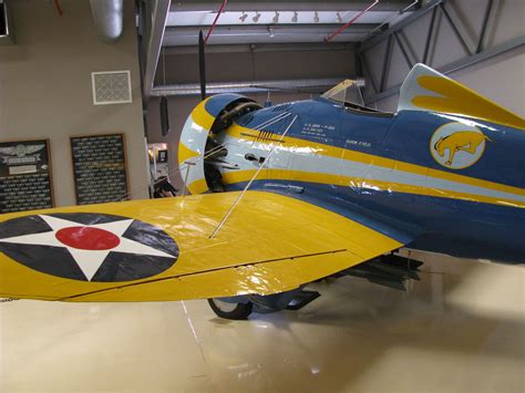 A Yellow And Blue Airplane Is On Display In A Museum Room With Other