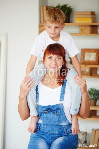 Portrait Of Mother With Son Sitting On Shoulders At Home