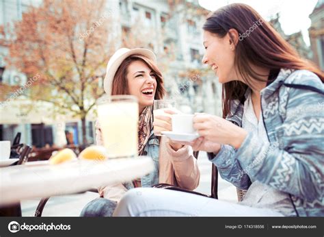 Two Friends Talking And Drinking Coffee Sitting In A Cafe Outdoor