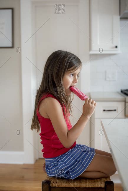 Girl On Stool Eating Popsicle Stock Photo Offset