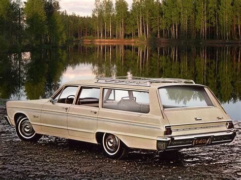 An Old Station Wagon Is Parked On The Shore Of A Lake With Trees In The