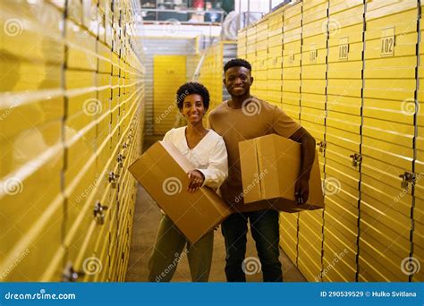 Curly Haired Guy And Girlfriend Are Standing In Warehouse With Cardboard Boxes Stock Image