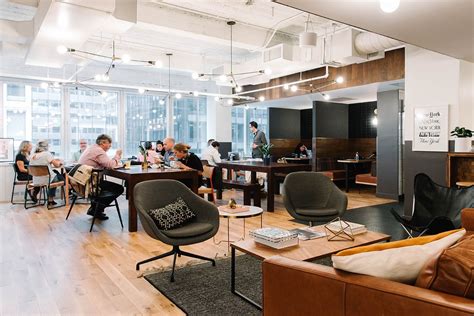 People Are Sitting At Tables In An Office With Chairs And Couches