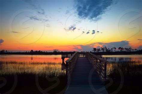 Brown Wooden River Dock On Clam Water During Sunset By Lexi Pernsteiner