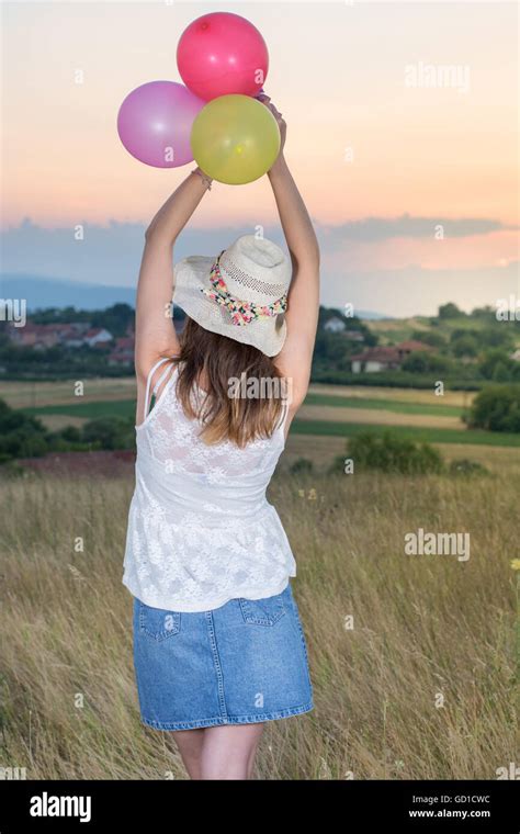 Young Woman Holding Balloons And Looking At Sunset Stock Photo Alamy