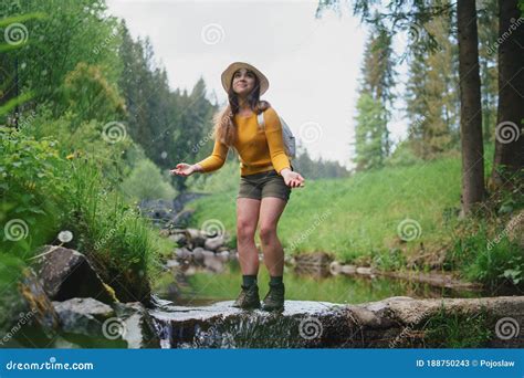 Happy Young Woman Standing By Stream On A Walk Outdoors In Summer