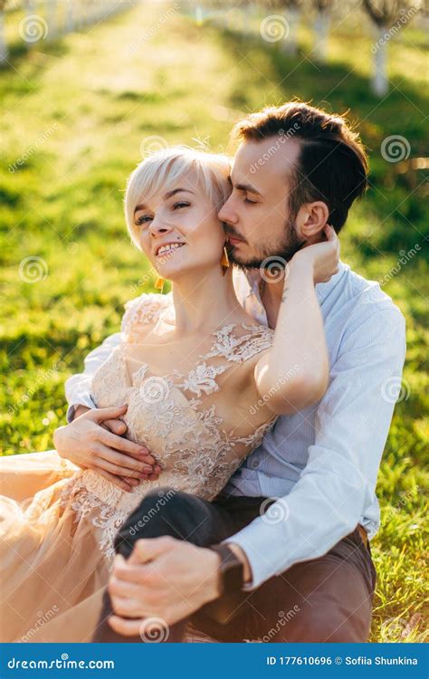 Young Couple In Spring Blossoming Garden Having Romantic Date Sitting On The Grass Pretty