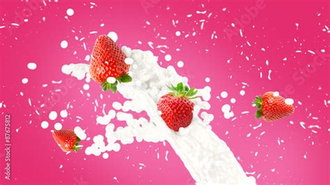 Strawberry In Milk Splash Over Pink Background Stock Photo And