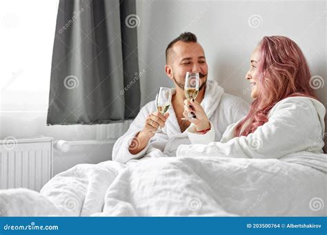 Beautiful Couple Have Romantic Time On Bed Drinking Champagne Stock
