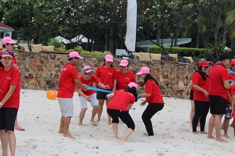 A Group Of People In Red Shirts Playing Frisbee On The Beach With Each