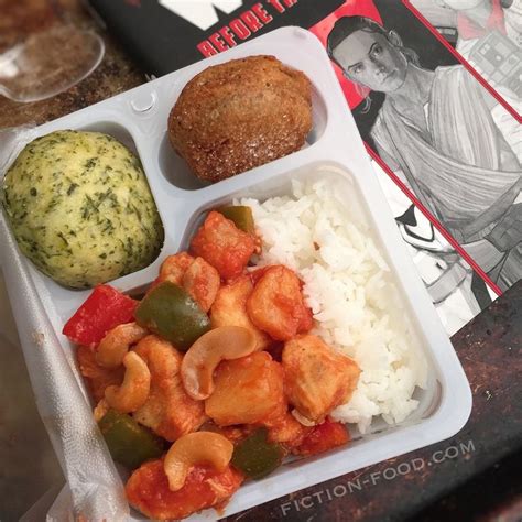 A Tray With Rice Meat And Vegetables On It Next To A Book About Food