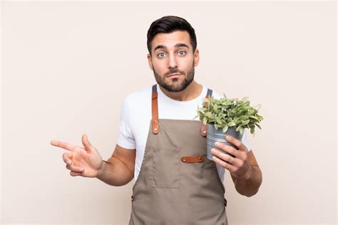 Hombre Jardinero Sosteniendo Una Planta Sobre Apuntando A Los Laterales Que Tienen Dudas Foto