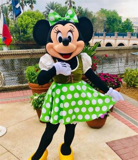 The Minnie Mouse Is Dressed In Green And White Polka Dot Skirt Yellow Shoes And A Bow On Her Head