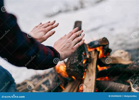 Man Warms Hands Of A Woman In His Hands Over Snow And Firewood Background Royalty Free Stock