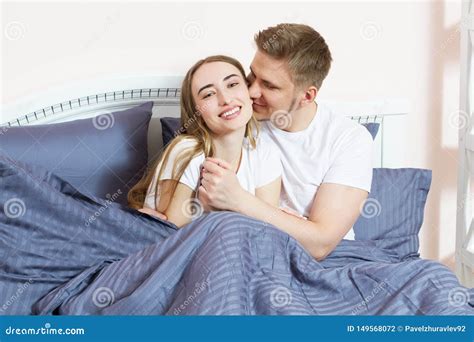 Young Man Kisses His Girlfriend In Bed In The Morning In The Bedroom