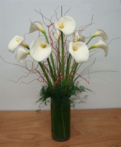 This Is A Floral Arrangement That Features Large White Calla Lilies With Accents Of Curly Willow